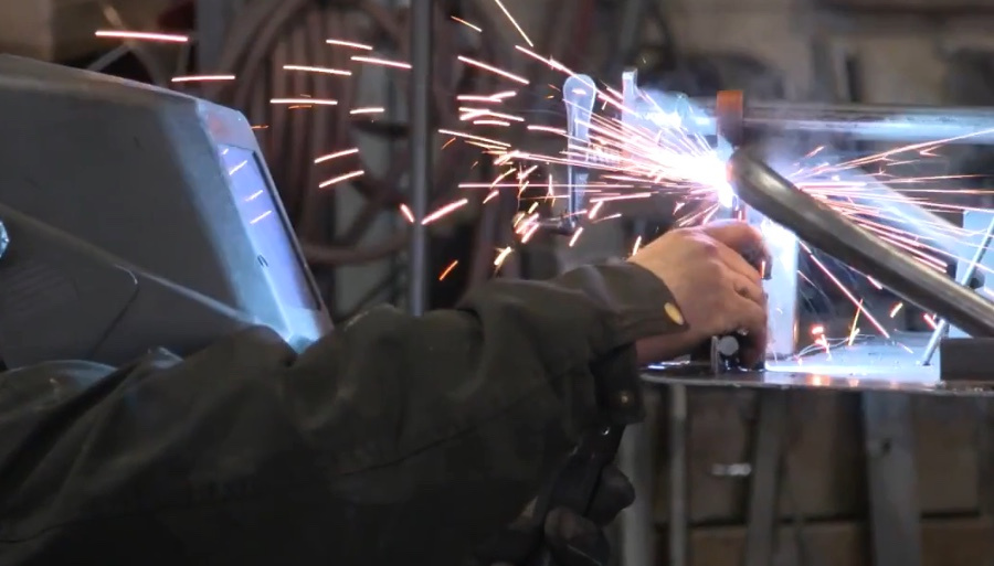 Bright sparks fly as a worker welds a metal component