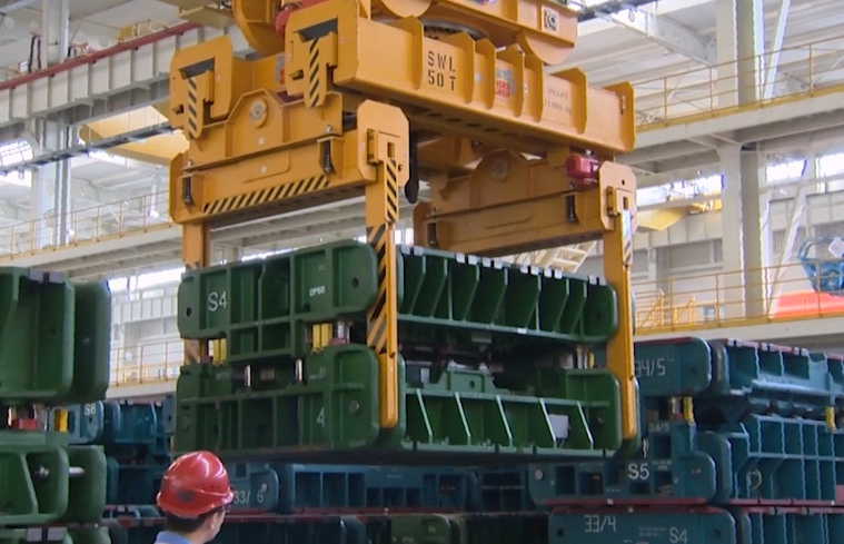 Overhead crane handling industrial tooling inside a manufacturing facility
