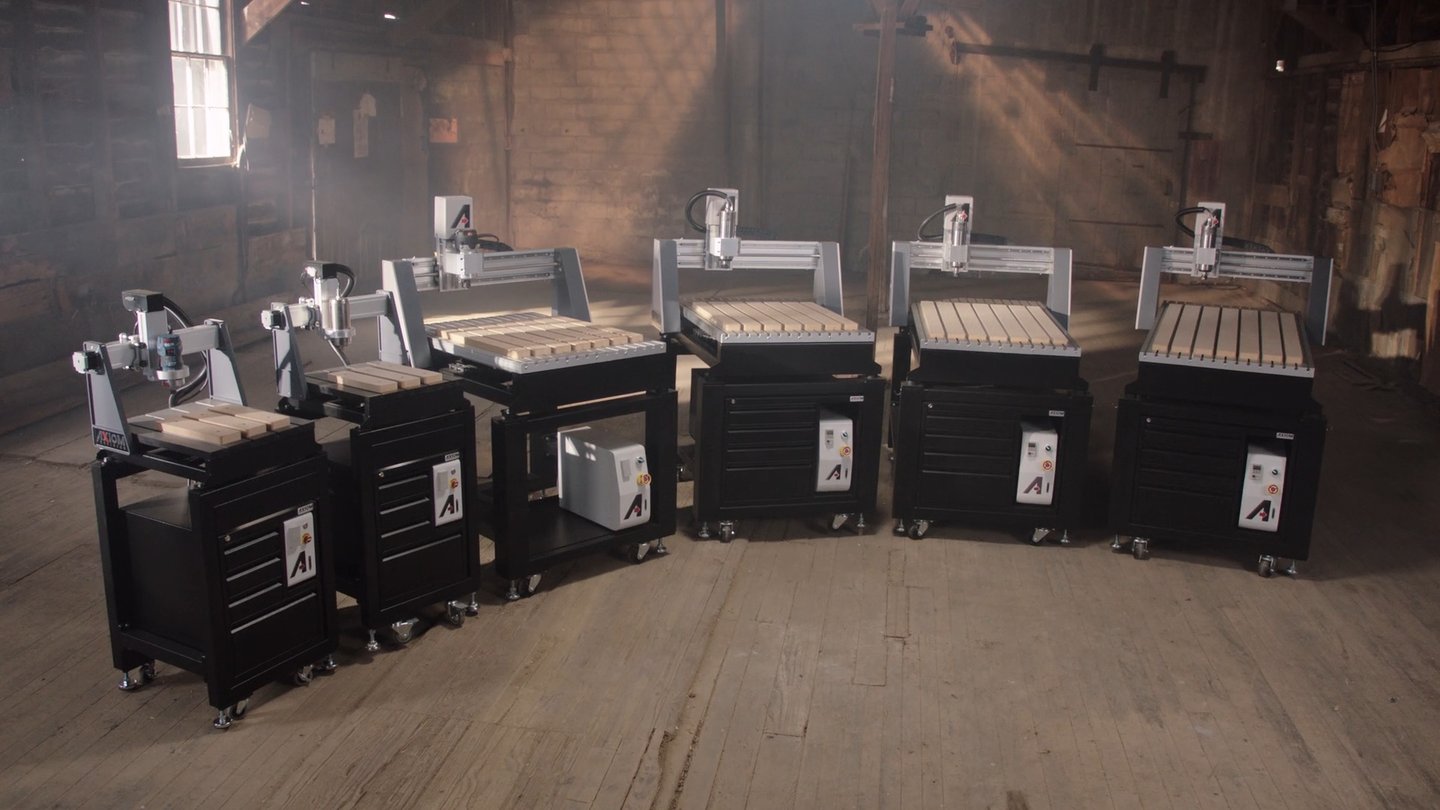 Six CNC routers arranged across a warm industrial interior