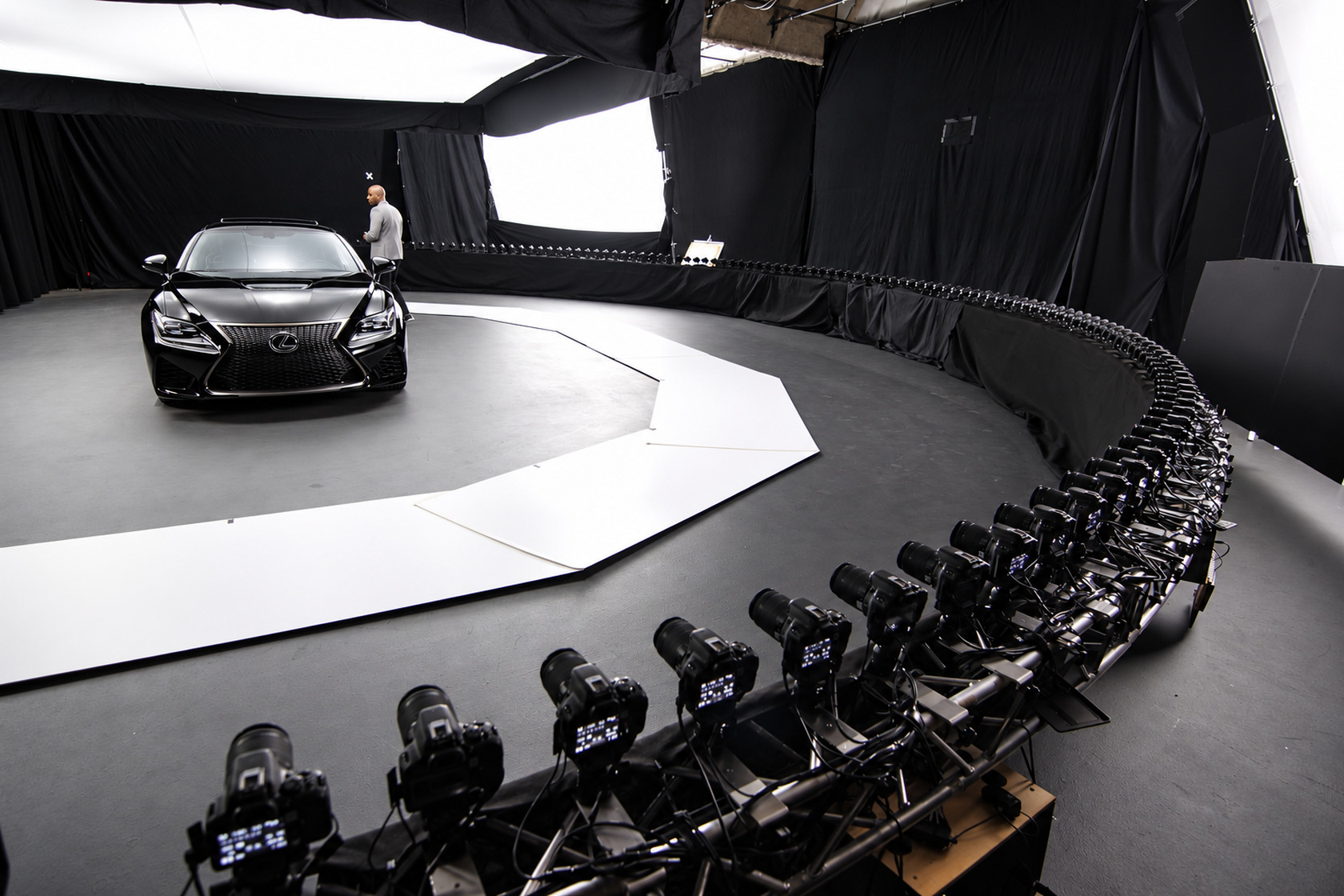 Black car on a studio stage surrounded by an arc of cameras