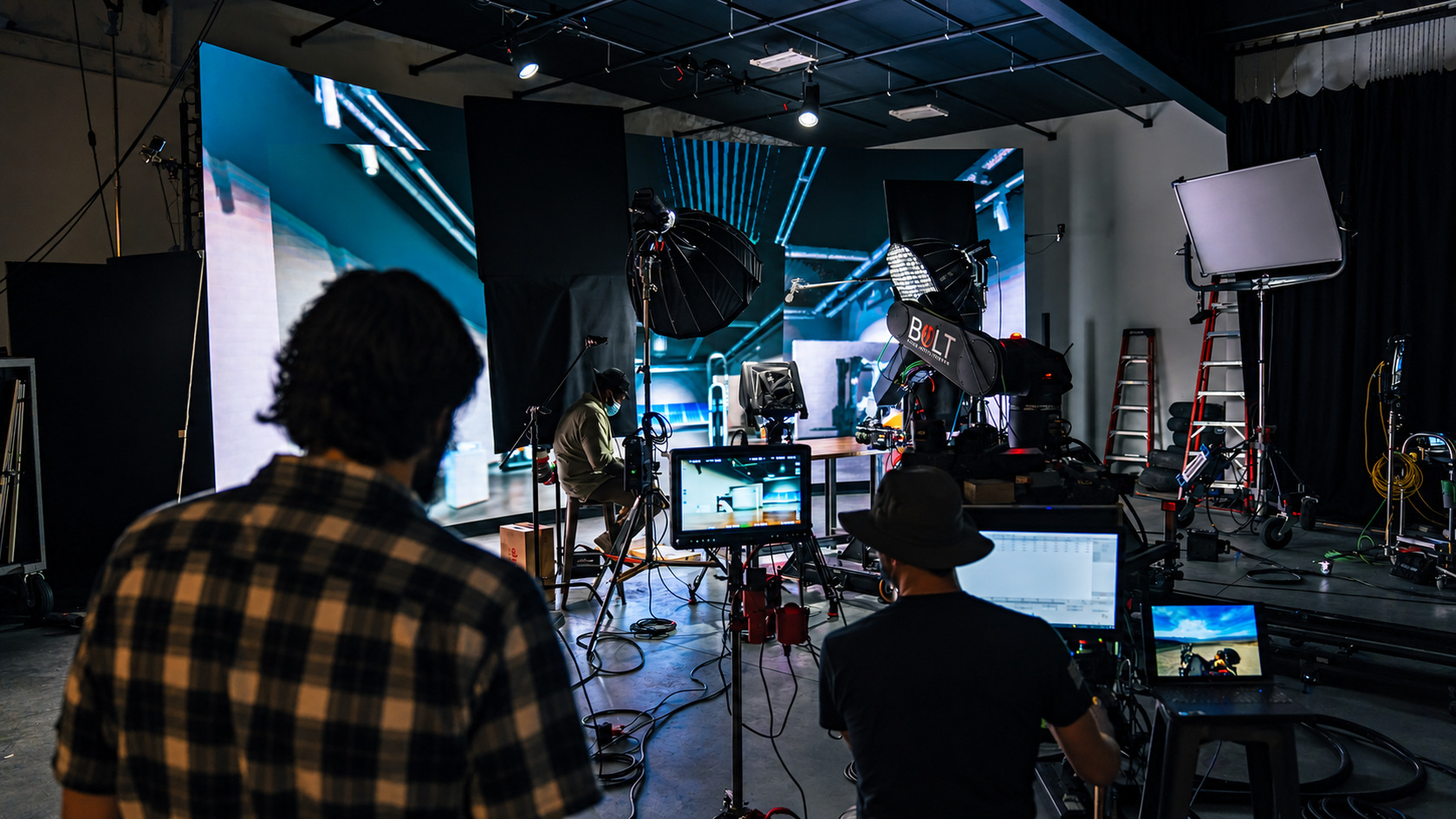 Crew watching production monitors beside a camera robot and LED wall