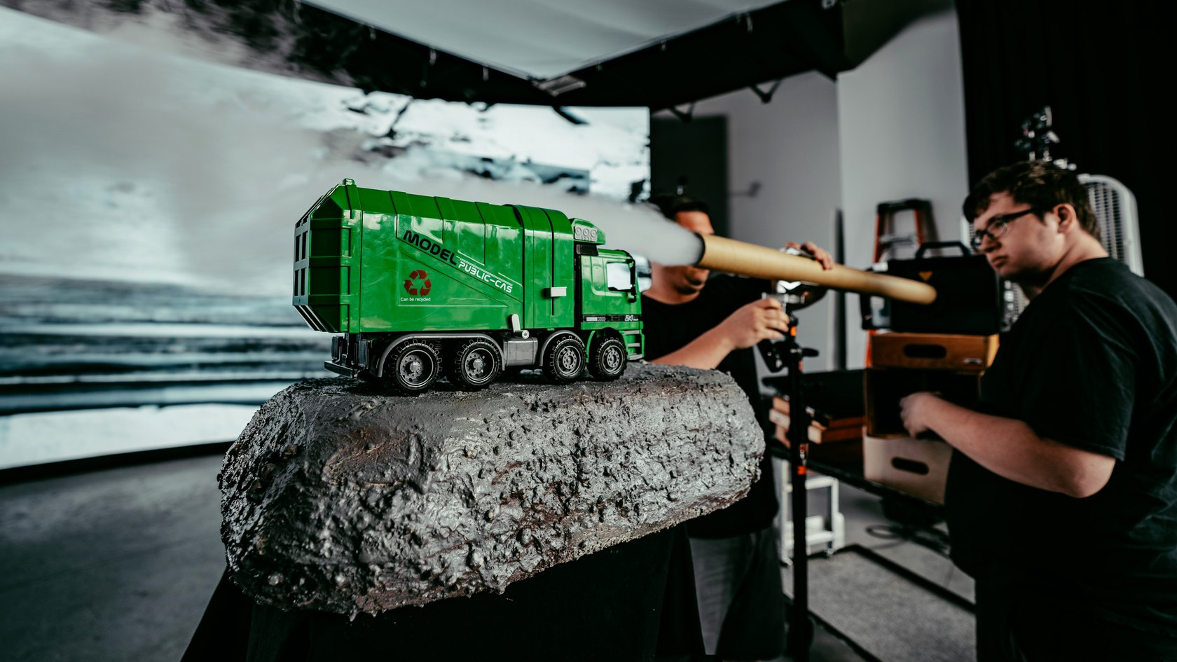 Crew adding a practical fog effect behind a miniature green truck on a rocky platform