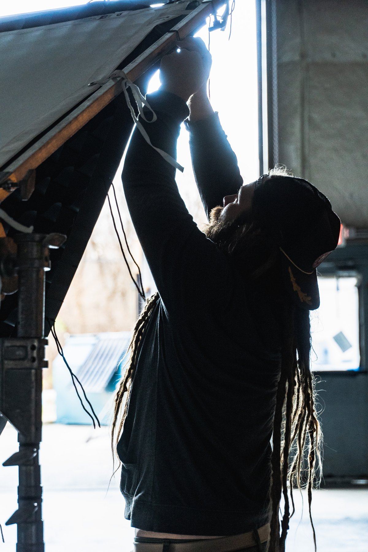 Crew member fastening an overhead lighting frame beside a window