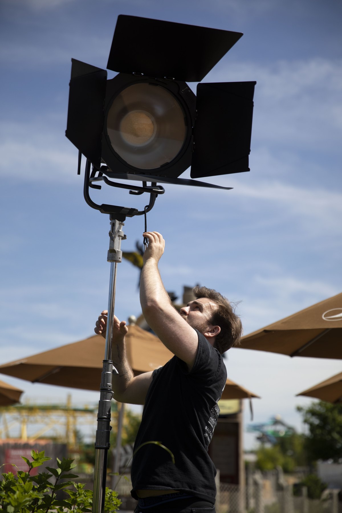 Crew member adjusting a large film light outdoors