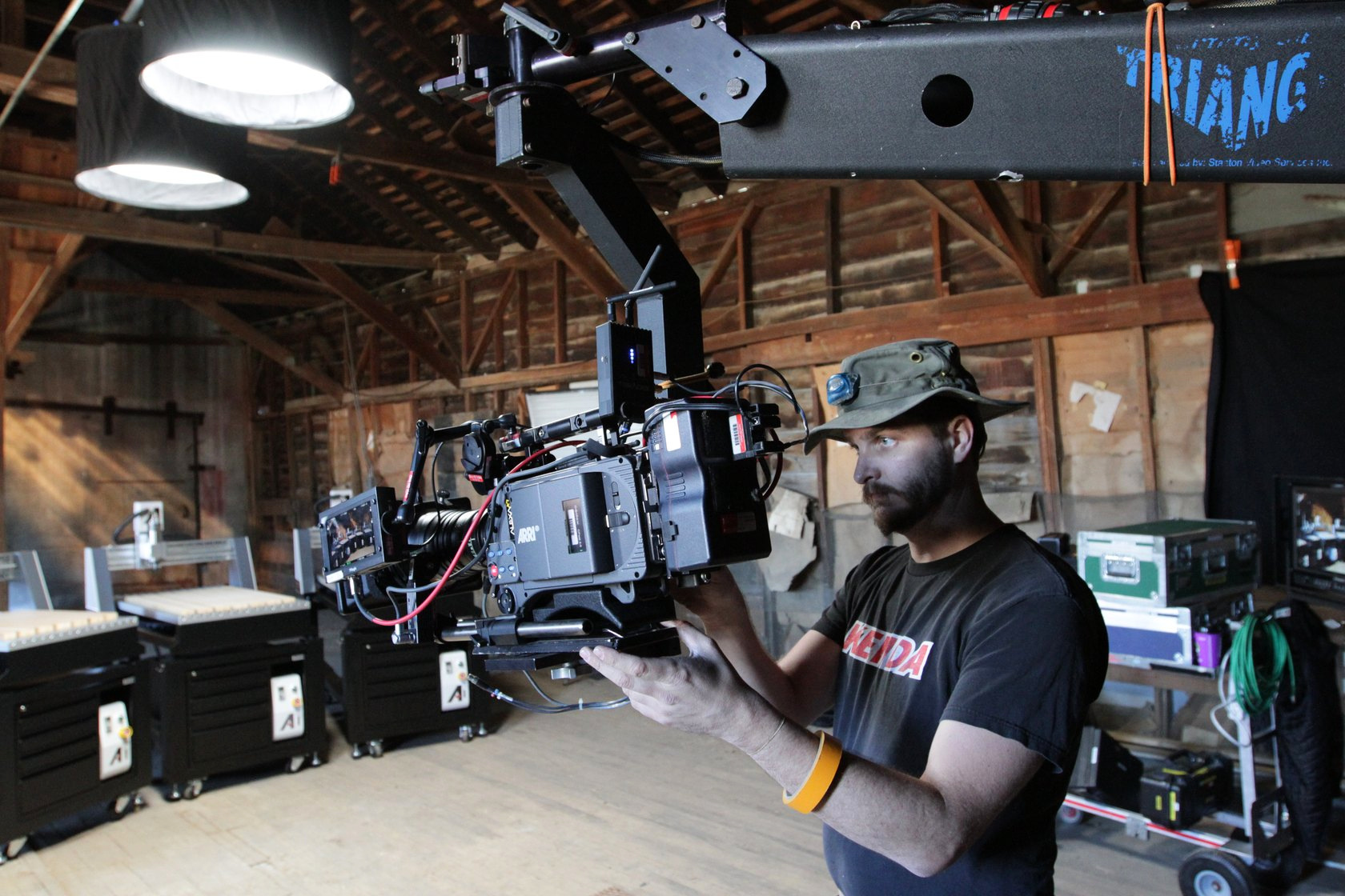 Camera operator adjusting a cinema camera mounted on a jib inside a timber building