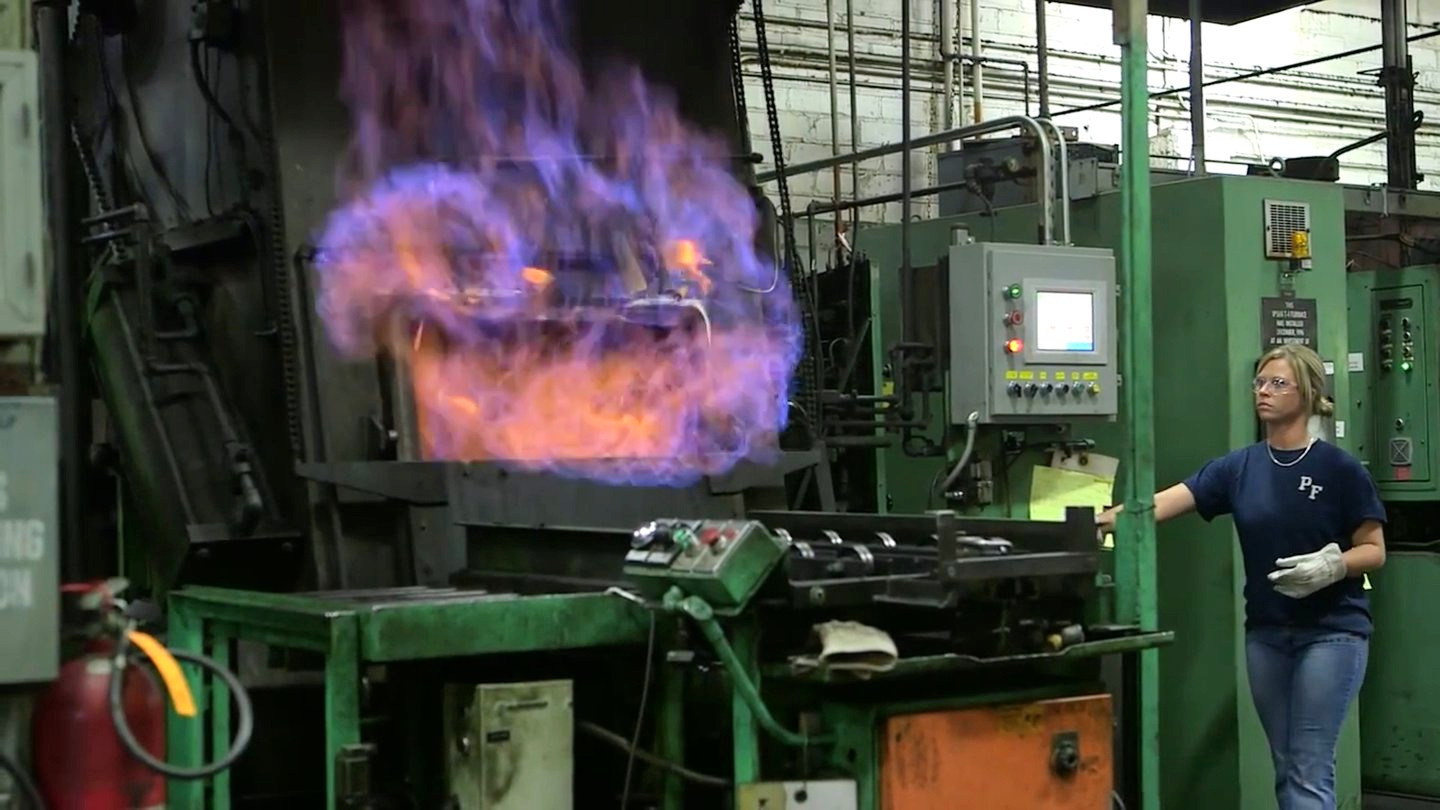 Worker beside a heat-treatment furnace