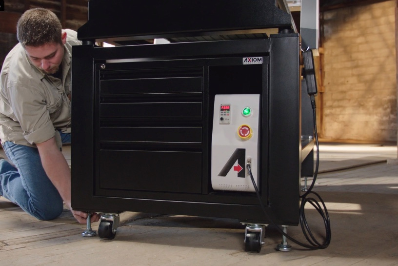 A technician adjusts the base of an Axiom CNC router during filming
