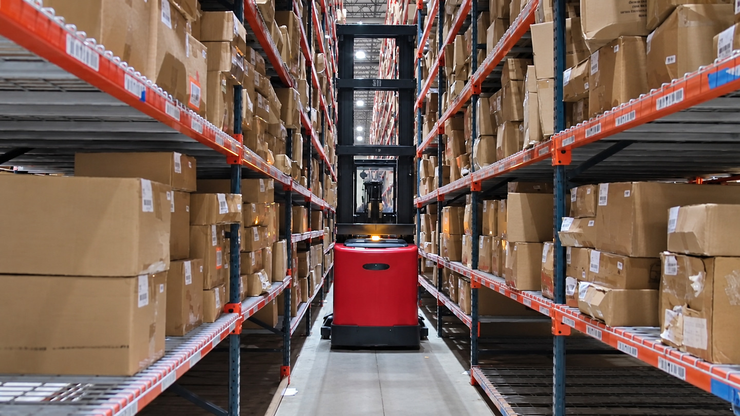 Warehouse lift between tall storage racks