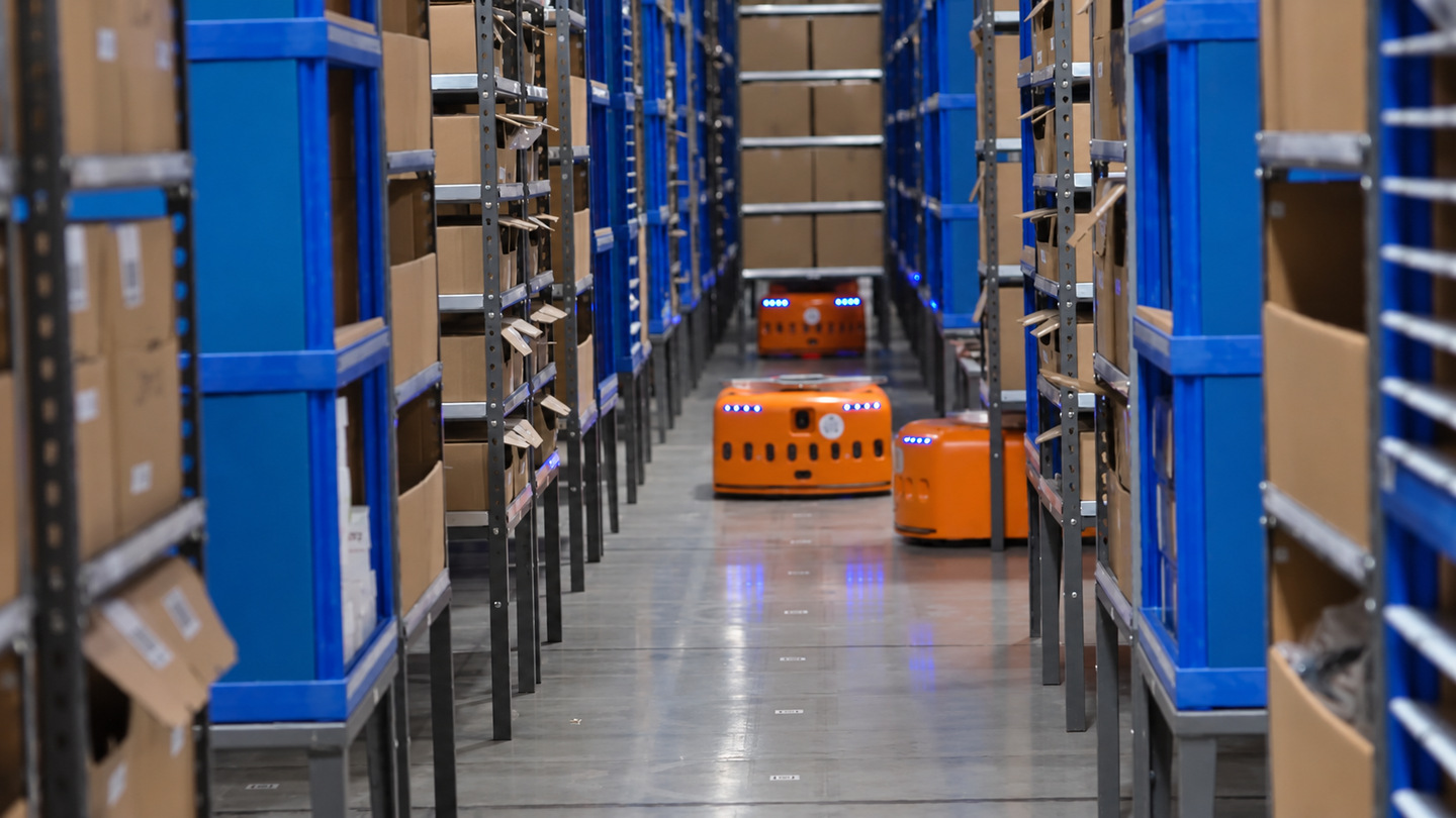 Orange warehouse robots between storage racks