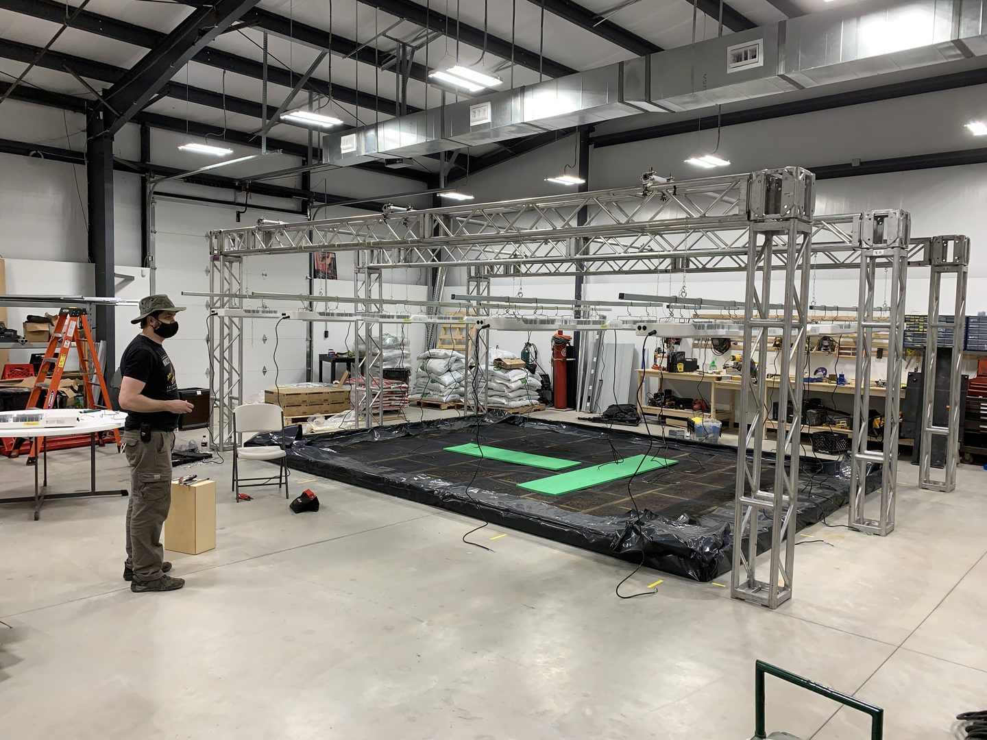 Crew member beside the truss structure for the studio grow bed