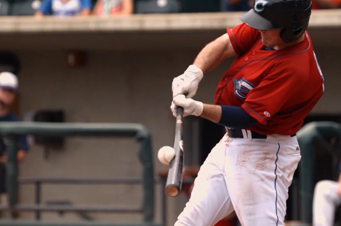 A baseball just before contact with a swinging bat